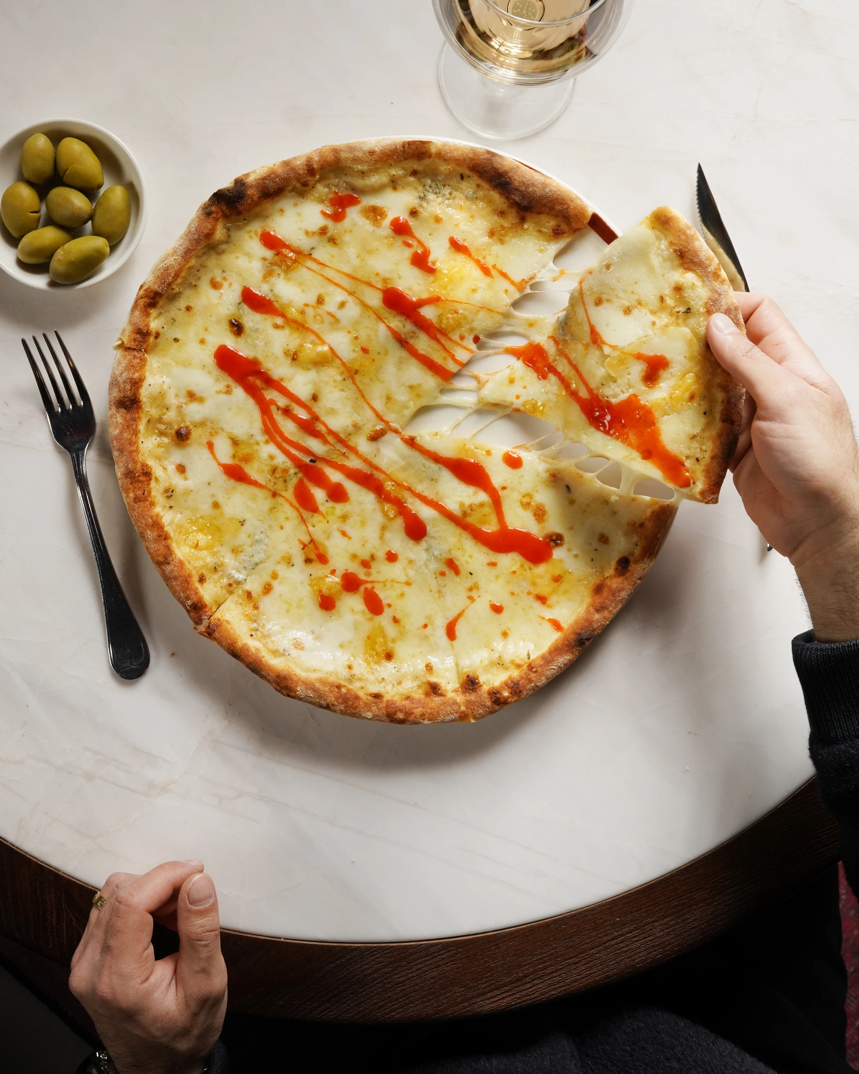 Mermer sofrada Biberify soslu pizzadan bir dilimi kaldıran el